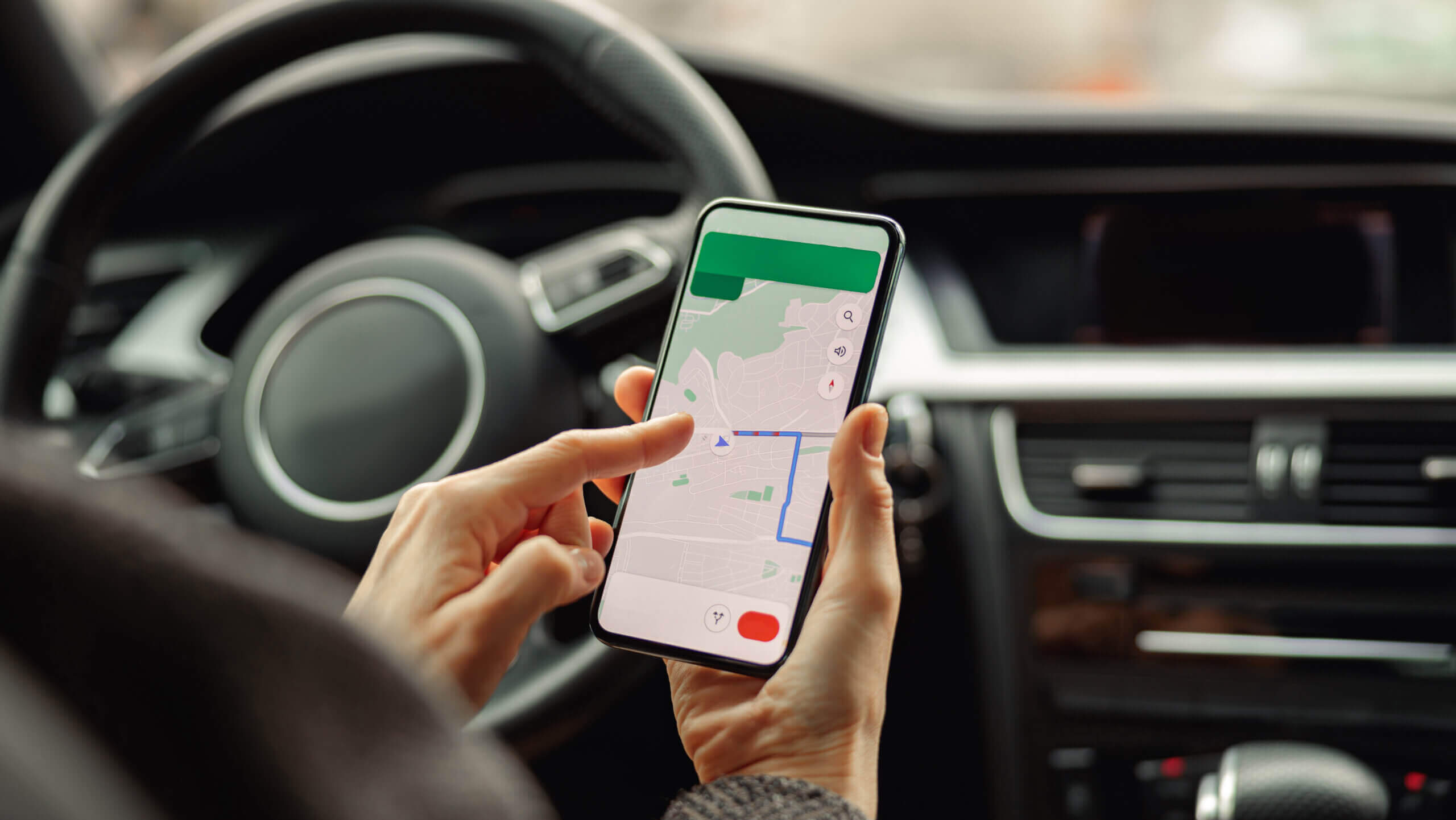 Person im Auto hält Smartphone mit Google Maps Karte sichtbar